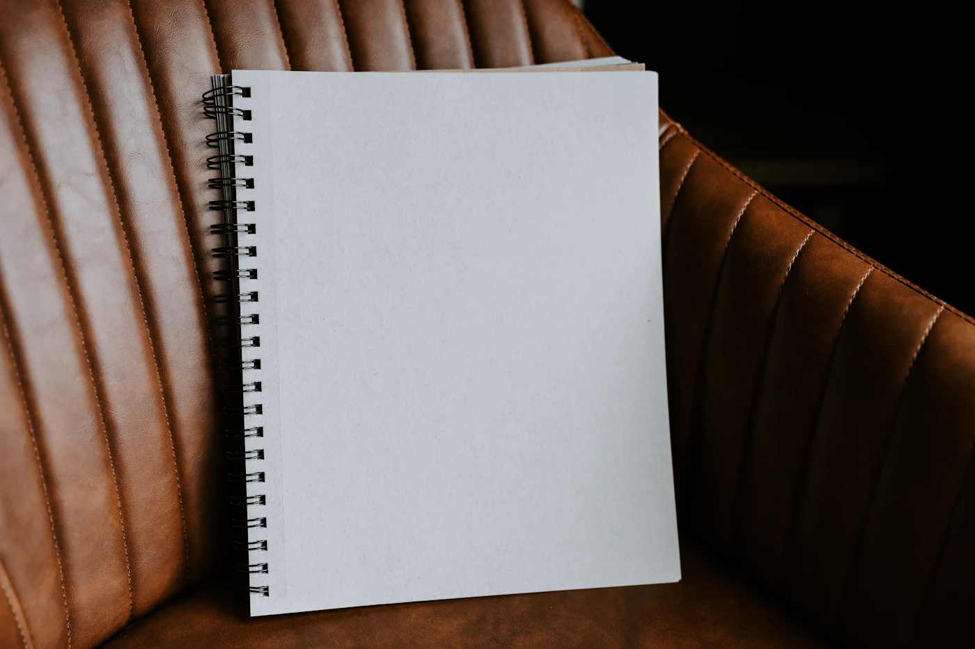 Notebook and pen resting on a leather chair, styled as a documentation and agreements workspace